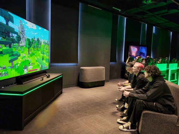 three people on a couch playing a game on a 98 inch Samsung NEO QLED 4K TV