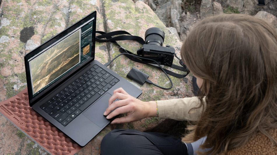 woman working outside with a Samsung laptop, camera, and portable T9 SSD
