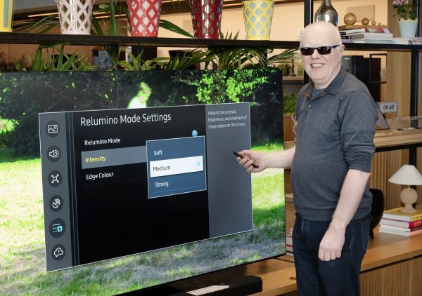 Robin Spinks smiling in front of a Samsung NEO QLED TV