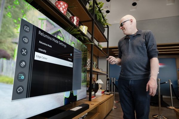 Robin Spinks holding a remote control and exploring Relumino Mode on a Samsung Neo QLED TV