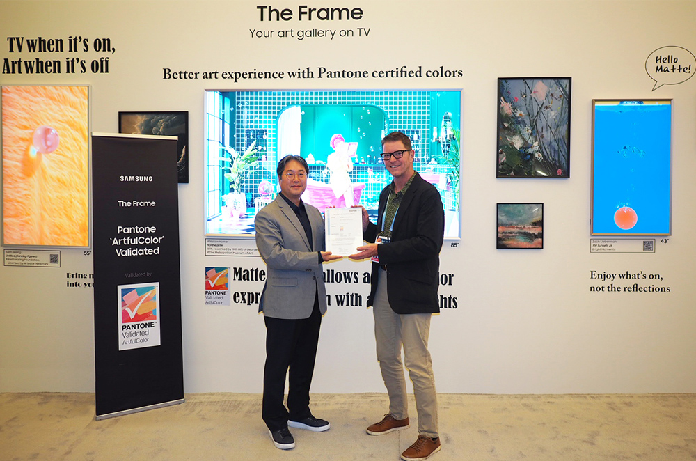 Two men holding a Pantone Certifcate in front of Samsung The Frame