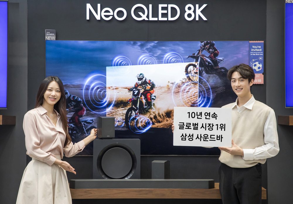 삼성전자 모델이 사운드바 10년 연속 글로벌 시장 1위 달성을 기념하며, 2024년형 사운드바 'HW-Q990D'와 2024년형 Neo QLED 8K 제품을 소개하고 있는 모습